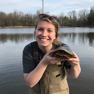 A photo of Emma Guelzow holding a turtle.
